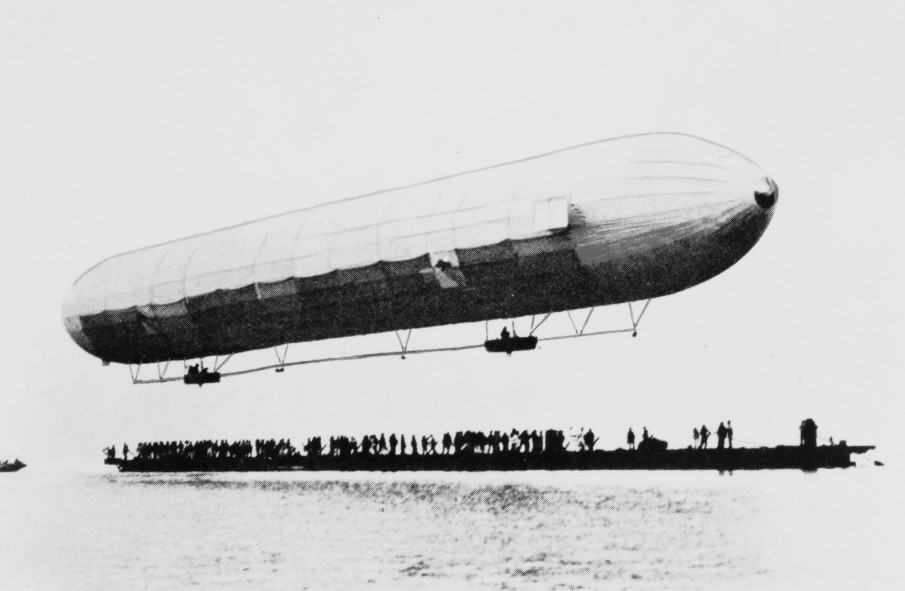 A black and white photograph of the Zeppelin LZ 1 taking flight over a crowd at Lake Constance in Germany