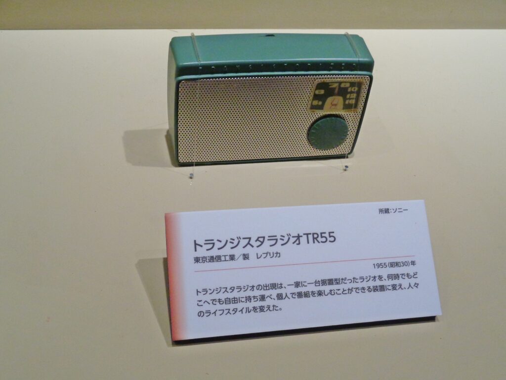 A photo of the TR-55 - a 1955 transistor radio with an aqua green frame, a silver grill front, and a dial & a series of numbers for channel selection